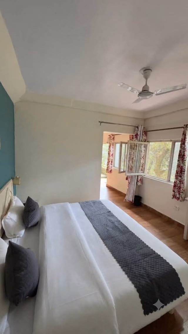 Deluxe room 303 with teal curtains at the window