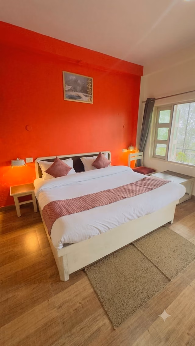 Standard room 201 with the bed against a red wall and the window beside it
